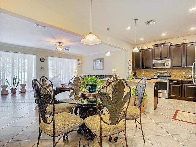 tiled dining area featuring ceiling fan and ornamental molding