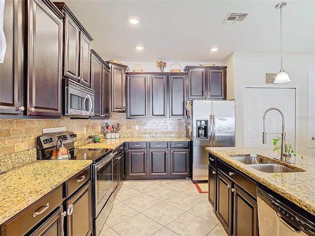 kitchen featuring hanging light fixtures, dark brown cabinets, sink, appliances with stainless steel finishes, and light stone counters