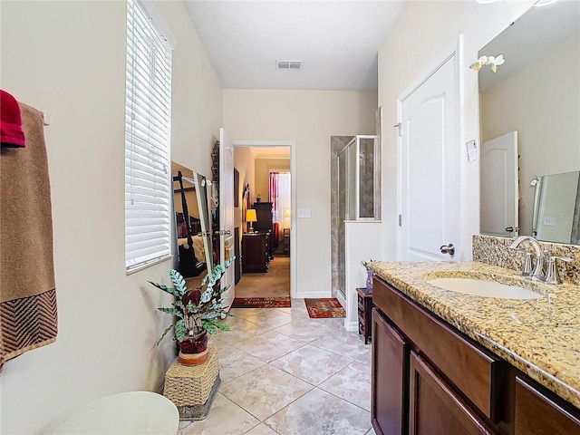 bathroom with a shower with door, vanity, and tile patterned flooring