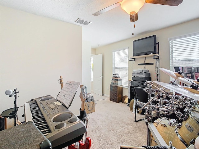 interior space with a textured ceiling, light colored carpet, and ceiling fan