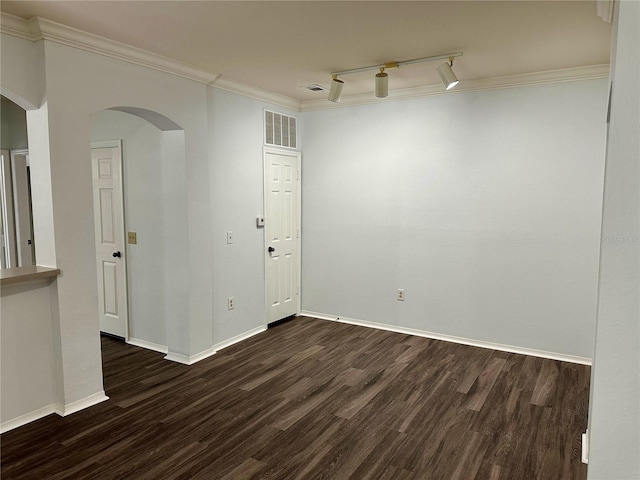 empty room with ornamental molding, track lighting, and dark hardwood / wood-style flooring