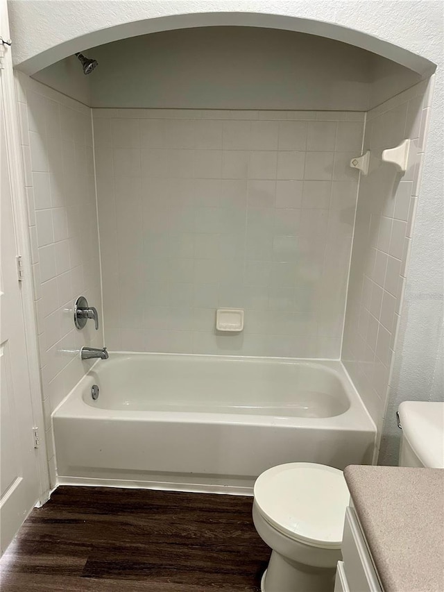 full bathroom featuring toilet, hardwood / wood-style floors, tiled shower / bath combo, and vanity