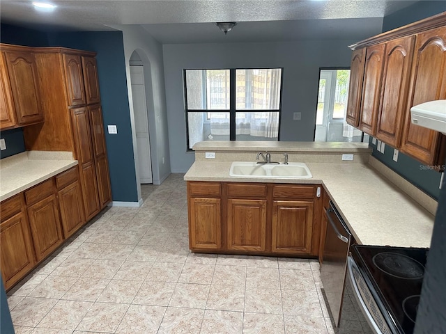 kitchen featuring kitchen peninsula, sink, light tile patterned floors, stainless steel dishwasher, and range