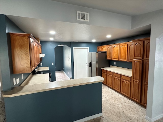 kitchen with stainless steel fridge, light tile patterned flooring, and kitchen peninsula