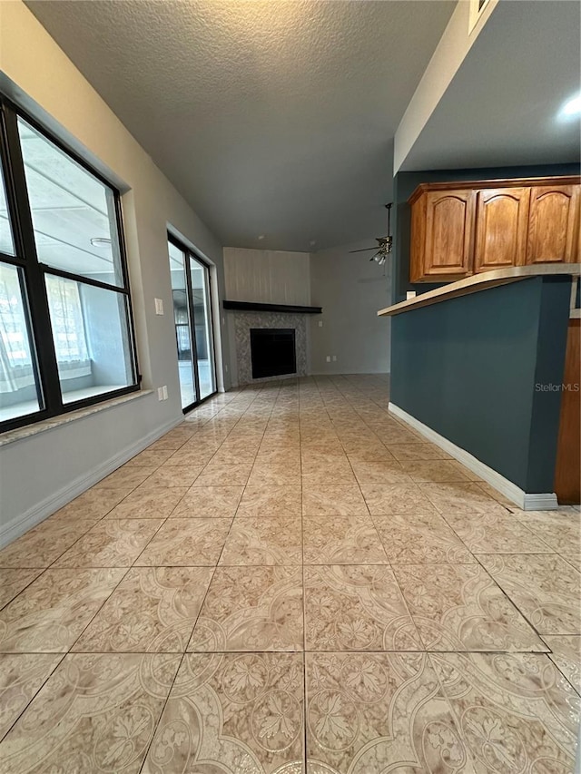 unfurnished living room with ceiling fan, a textured ceiling, and light tile patterned floors