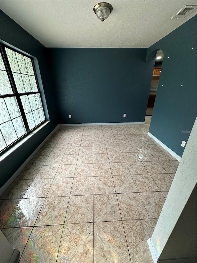 tiled spare room featuring a textured ceiling