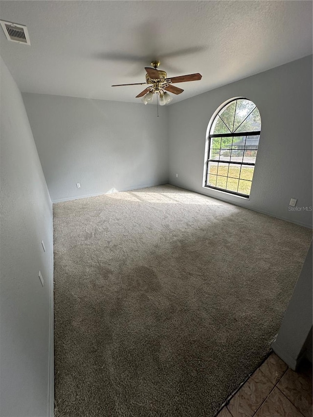 spare room with a textured ceiling, carpet, and ceiling fan