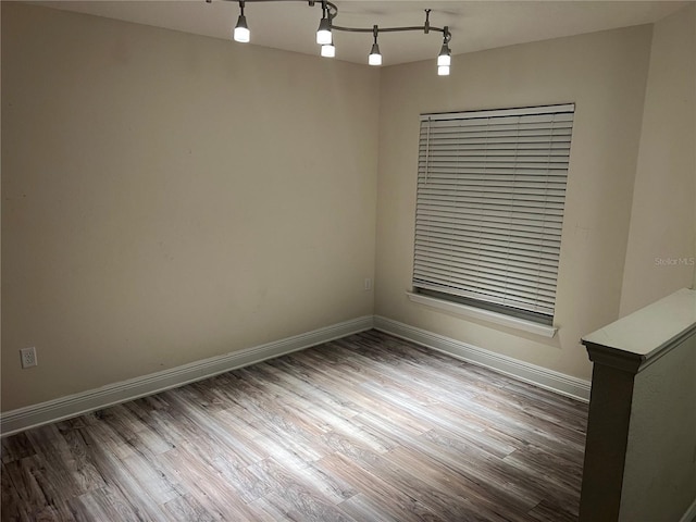 unfurnished room featuring rail lighting and dark wood-type flooring