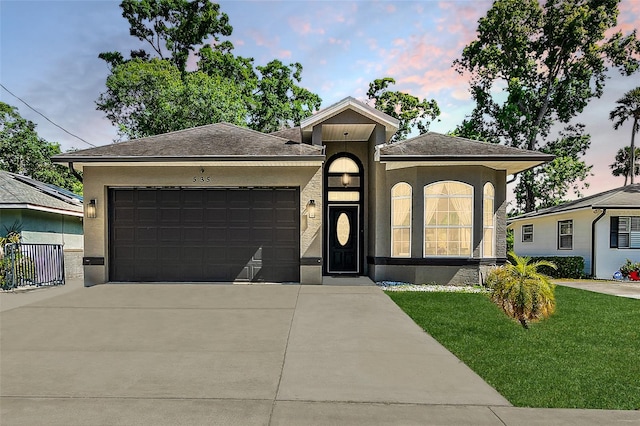 view of front of home with a garage and a lawn