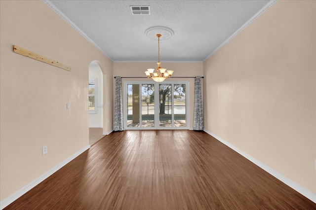 unfurnished dining area with ornamental molding, dark wood-type flooring, a textured ceiling, and an inviting chandelier