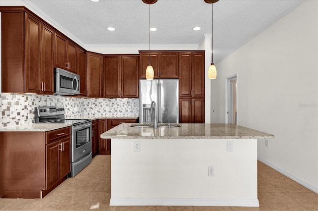 kitchen featuring light stone counters, appliances with stainless steel finishes, hanging light fixtures, and a kitchen island with sink