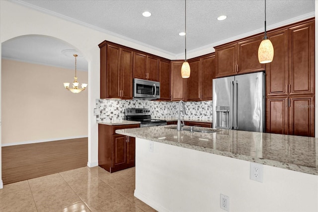 kitchen featuring light stone counters, appliances with stainless steel finishes, pendant lighting, crown molding, and sink