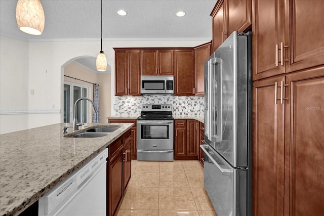 kitchen featuring tasteful backsplash, appliances with stainless steel finishes, light stone countertops, pendant lighting, and sink