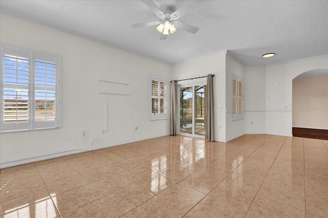 spare room featuring a textured ceiling, ceiling fan, light tile patterned flooring, and a wealth of natural light