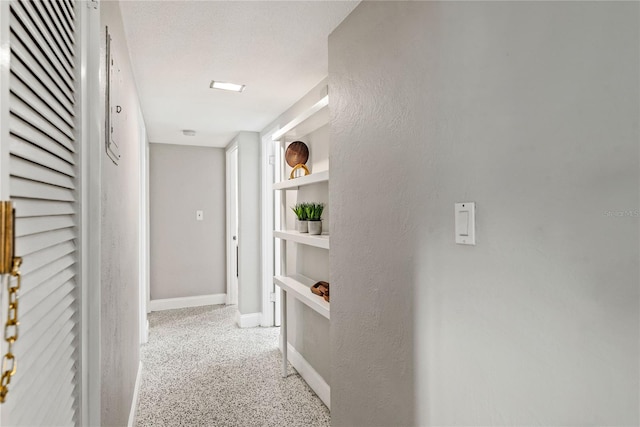 hallway featuring built in shelves and light carpet