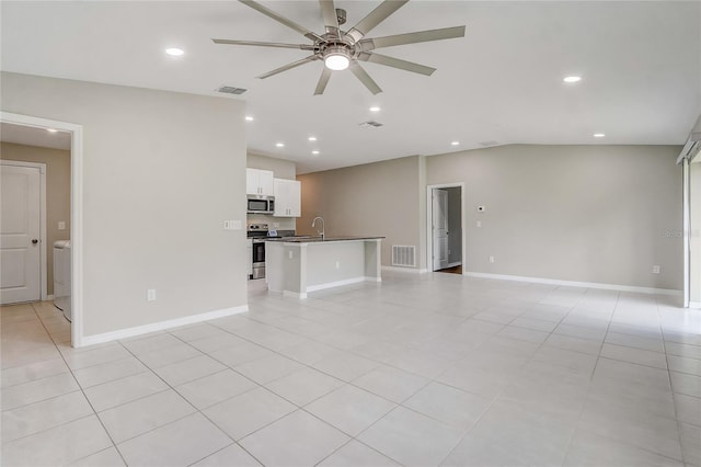 unfurnished living room with sink, washer / clothes dryer, ceiling fan, and light tile patterned floors