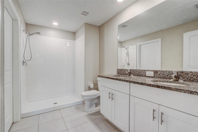 bathroom featuring vanity, a tile shower, toilet, and tile patterned flooring