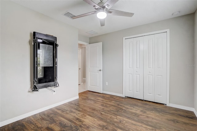 unfurnished bedroom featuring dark hardwood / wood-style floors, a closet, and ceiling fan