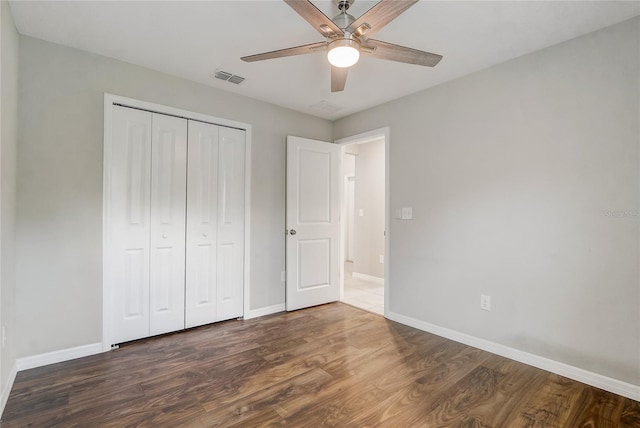 unfurnished bedroom with a closet, dark wood-type flooring, and ceiling fan