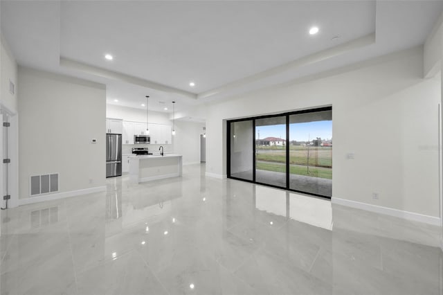 unfurnished living room with a raised ceiling and sink