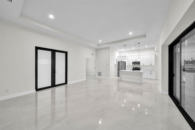 unfurnished living room featuring french doors and a tray ceiling