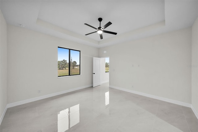 empty room featuring ceiling fan and a tray ceiling