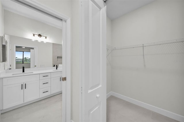 spacious closet featuring sink and light tile patterned floors