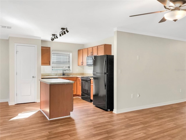 kitchen with sink, black appliances, a center island, crown molding, and light wood-type flooring