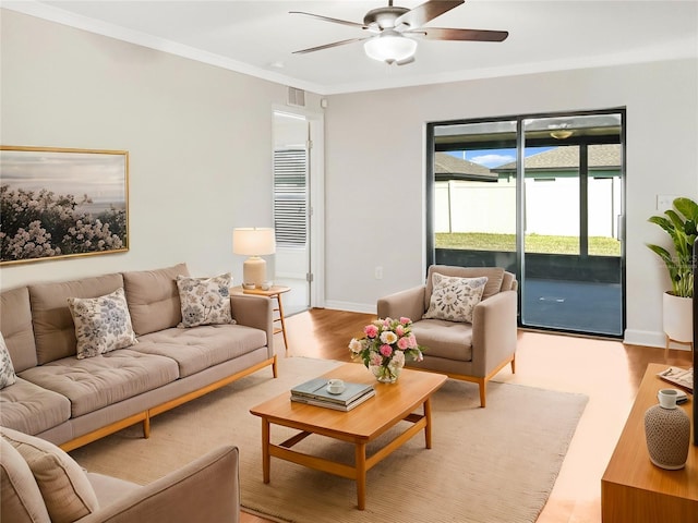 living room with light hardwood / wood-style floors, ornamental molding, and ceiling fan