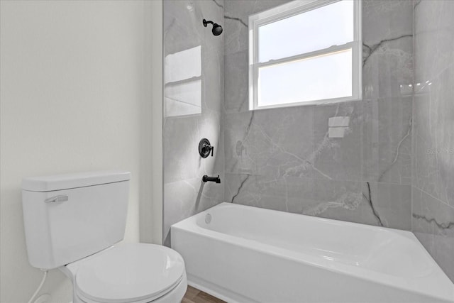 bathroom featuring toilet and tiled shower / bath