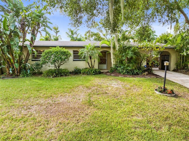 ranch-style house with concrete driveway, a front yard, and stucco siding