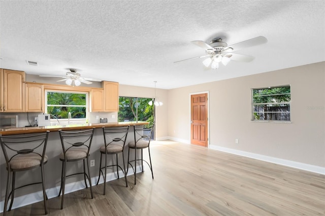 kitchen featuring light brown cabinets, hanging light fixtures, and light wood-type flooring