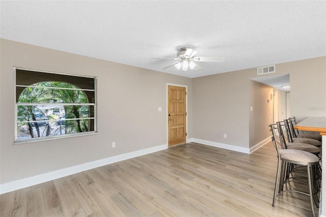 interior space with a ceiling fan, baseboards, visible vents, and light wood-type flooring