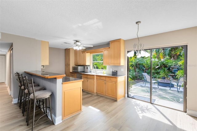 kitchen with a breakfast bar, light brown cabinets, kitchen peninsula, and light wood-type flooring