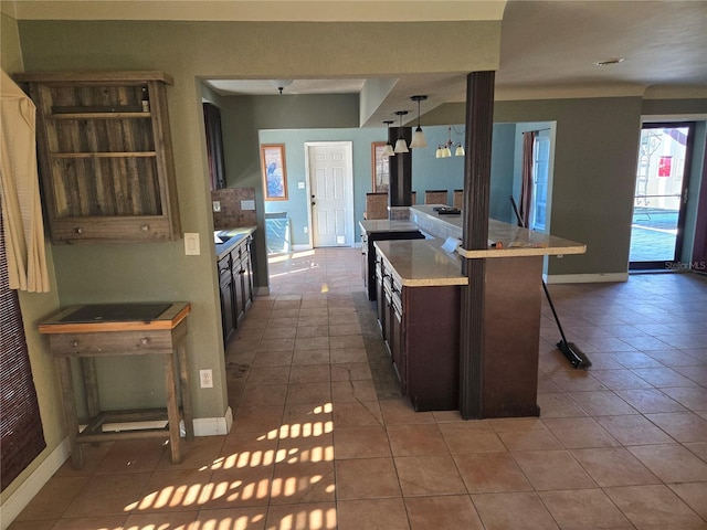 kitchen featuring dark brown cabinetry, a kitchen breakfast bar, tile patterned floors, an island with sink, and pendant lighting