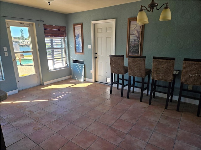 dining space featuring tile patterned floors, a notable chandelier, and a water view