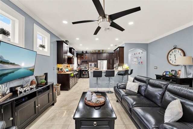 living room with ceiling fan, ornamental molding, and light tile patterned flooring