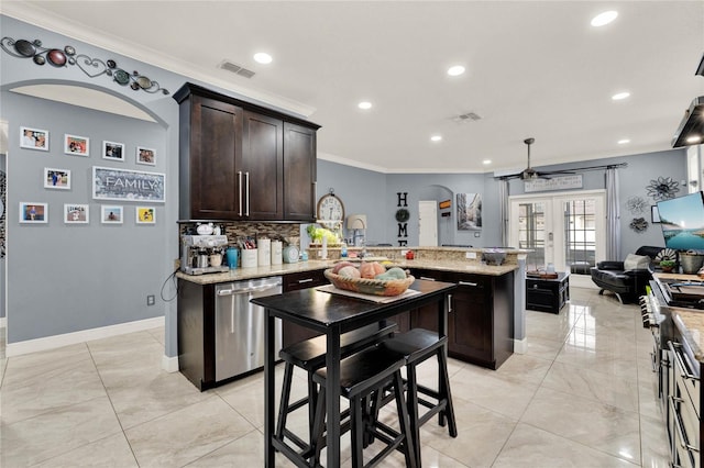 kitchen featuring appliances with stainless steel finishes, a kitchen island, backsplash, dark brown cabinets, and crown molding