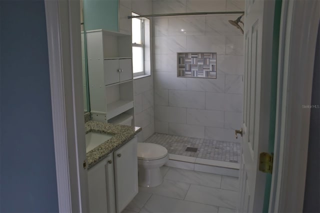 bathroom with toilet, vanity, and a tile shower