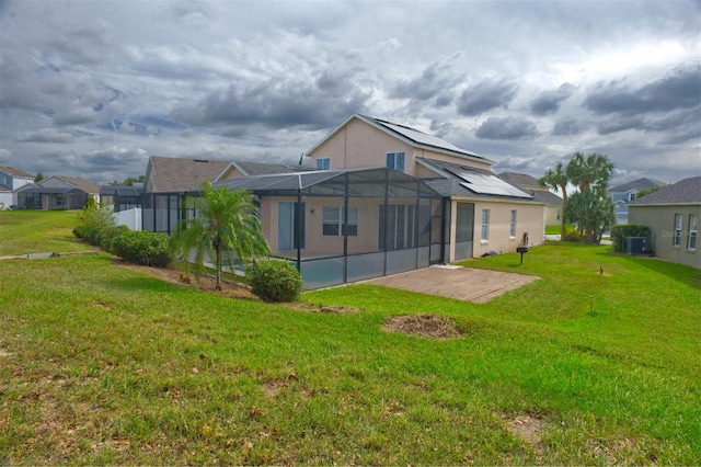 rear view of house featuring a patio area, a lawn, and glass enclosure