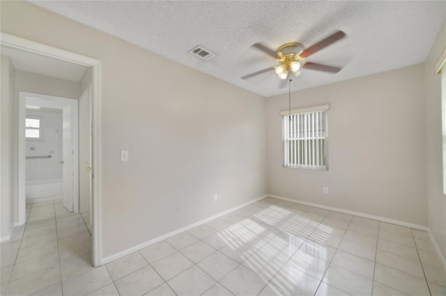 tiled empty room featuring a textured ceiling and ceiling fan