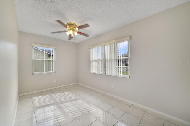 tiled empty room with ceiling fan, a textured ceiling, and plenty of natural light