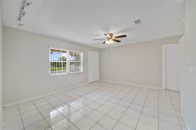 tiled spare room with track lighting, a textured ceiling, and ceiling fan