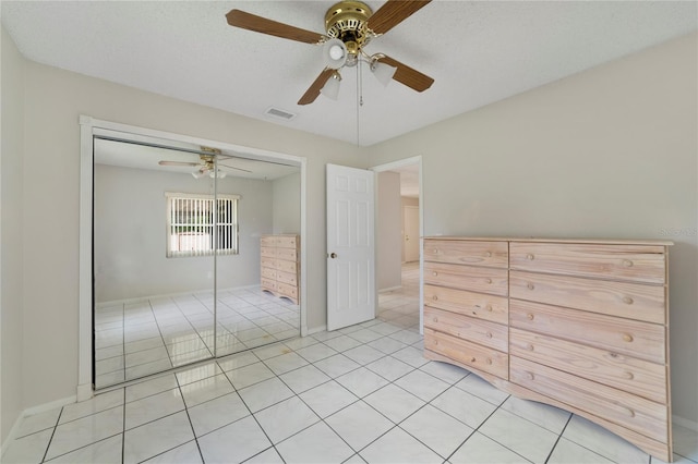 unfurnished bedroom featuring a closet, a textured ceiling, light tile patterned flooring, and ceiling fan