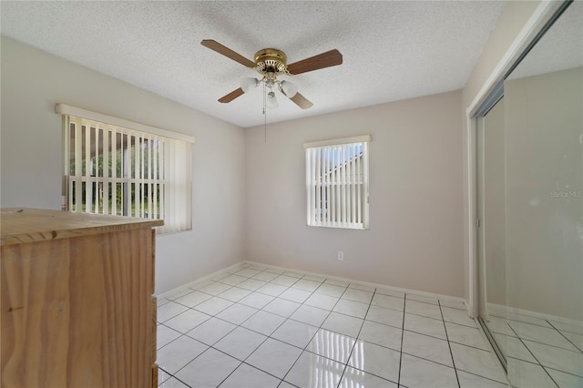 tiled empty room with a textured ceiling and ceiling fan