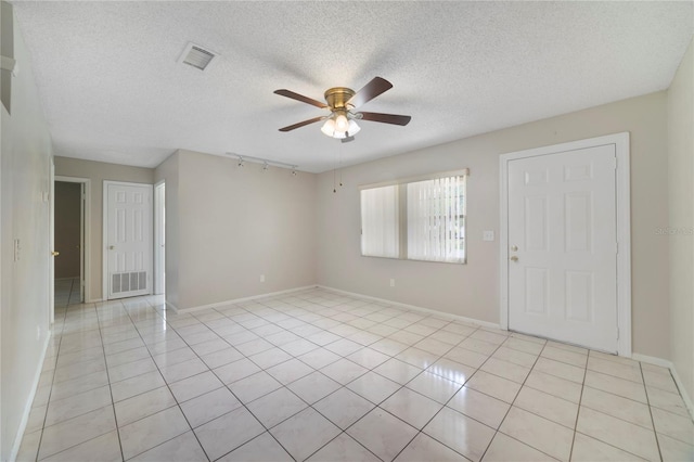 tiled spare room with rail lighting, ceiling fan, and a textured ceiling