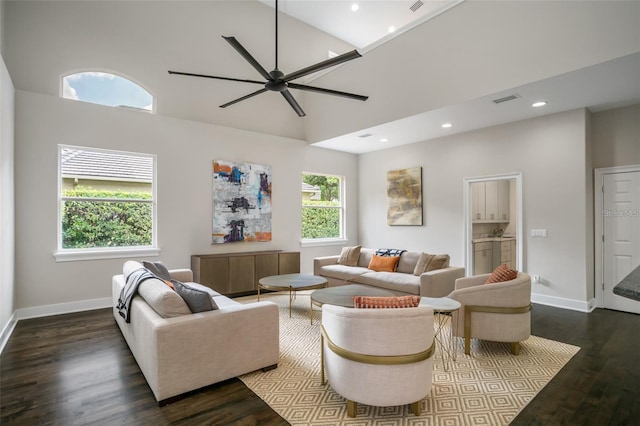 living room featuring dark hardwood / wood-style flooring, a towering ceiling, and ceiling fan