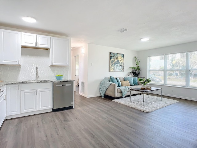 kitchen featuring white cabinets, sink, light stone counters, stainless steel dishwasher, and light hardwood / wood-style flooring