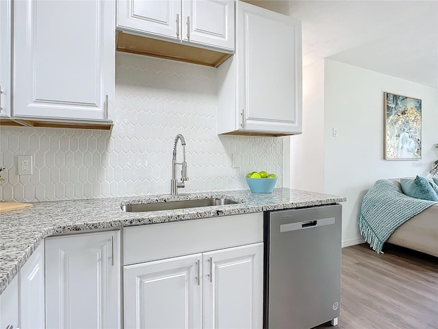 kitchen featuring sink, white cabinetry, stainless steel dishwasher, and light hardwood / wood-style flooring