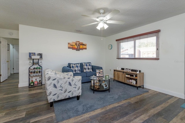 living room featuring dark wood-type flooring, ceiling fan, and a textured ceiling